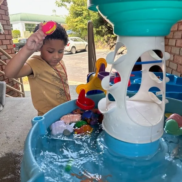 A child exploring a water table outdoors